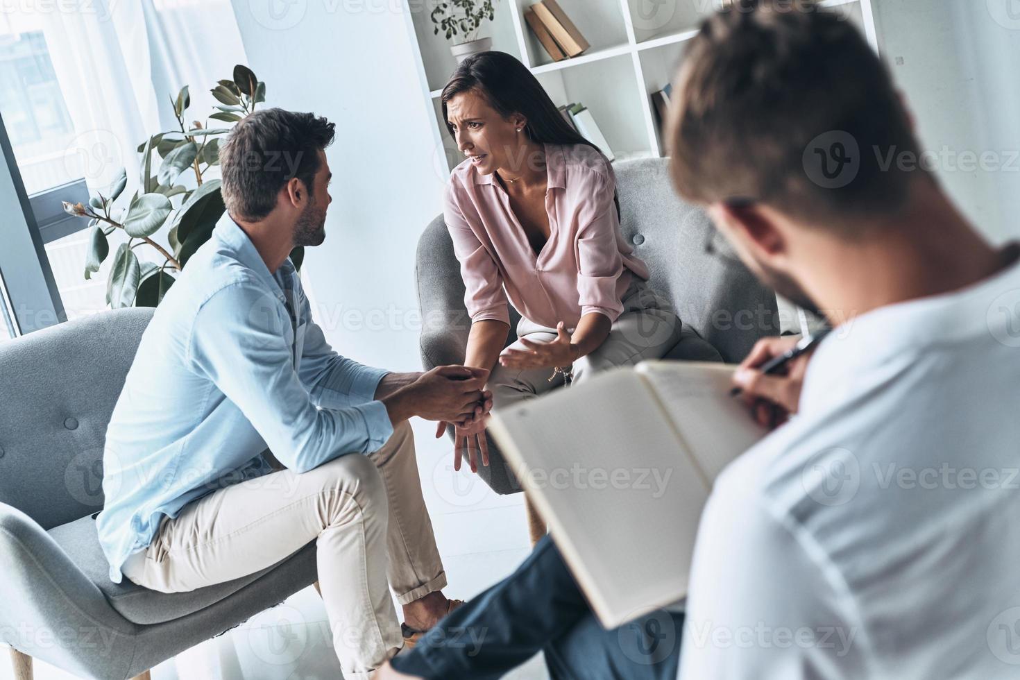 Helping people. Young married couple talking while sitting on the therapy session with psychologist photo