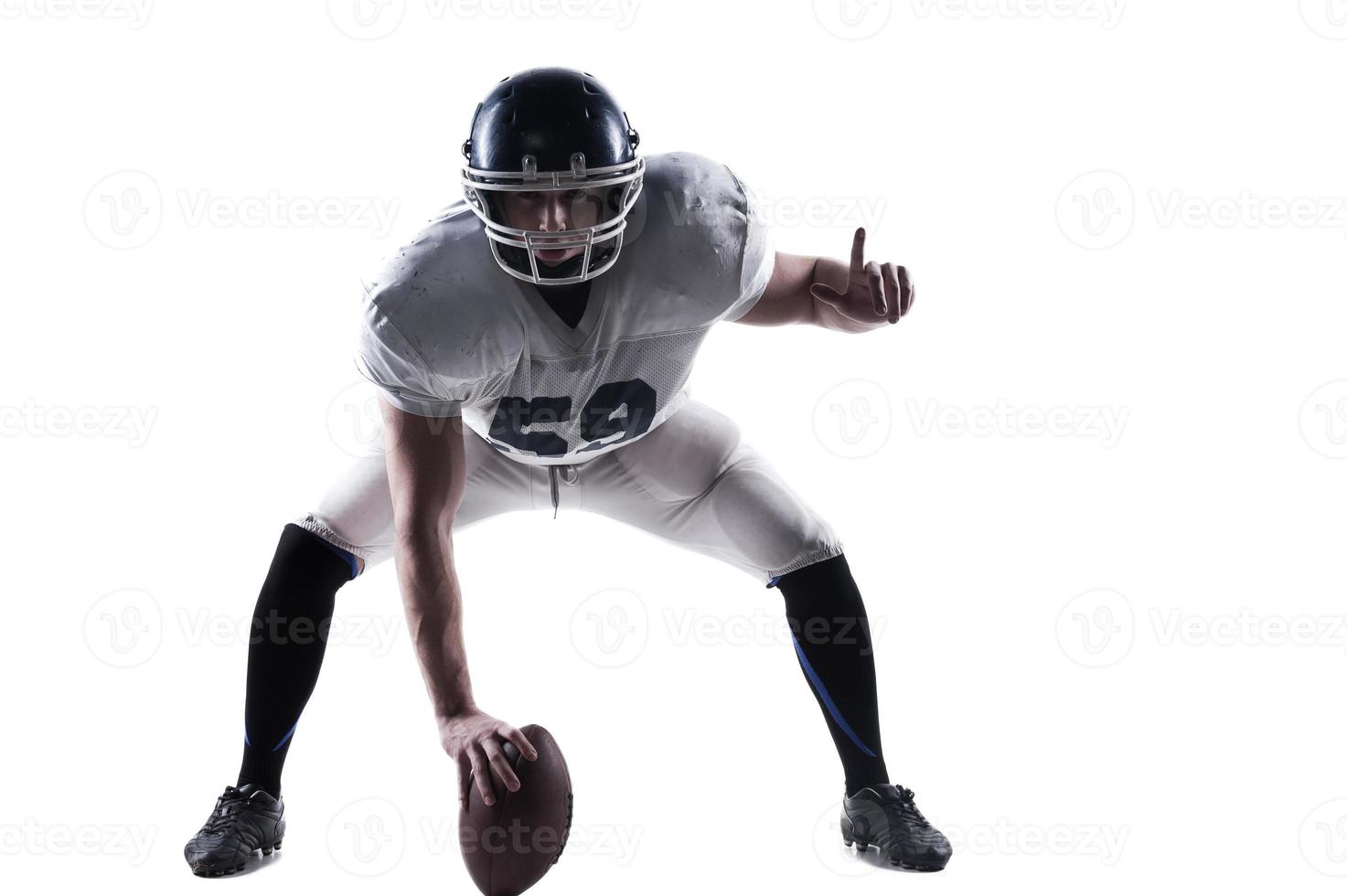 Full readiness.  American football player getting ready before throwing ball while standing against white background photo