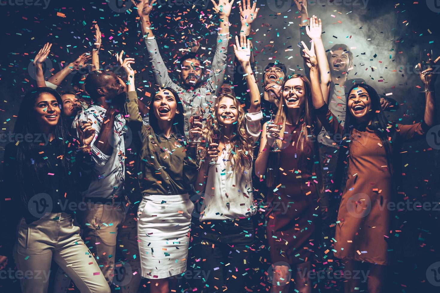 What a night Group of beautiful young people throwing colorful confetti and looking happy photo