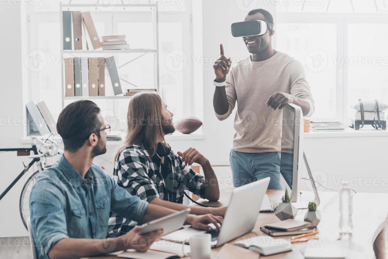 así que un equipo de desarrollo real coopera en su oficina mientras un joven apuesto ajusta los auriculares vr y sonríe foto