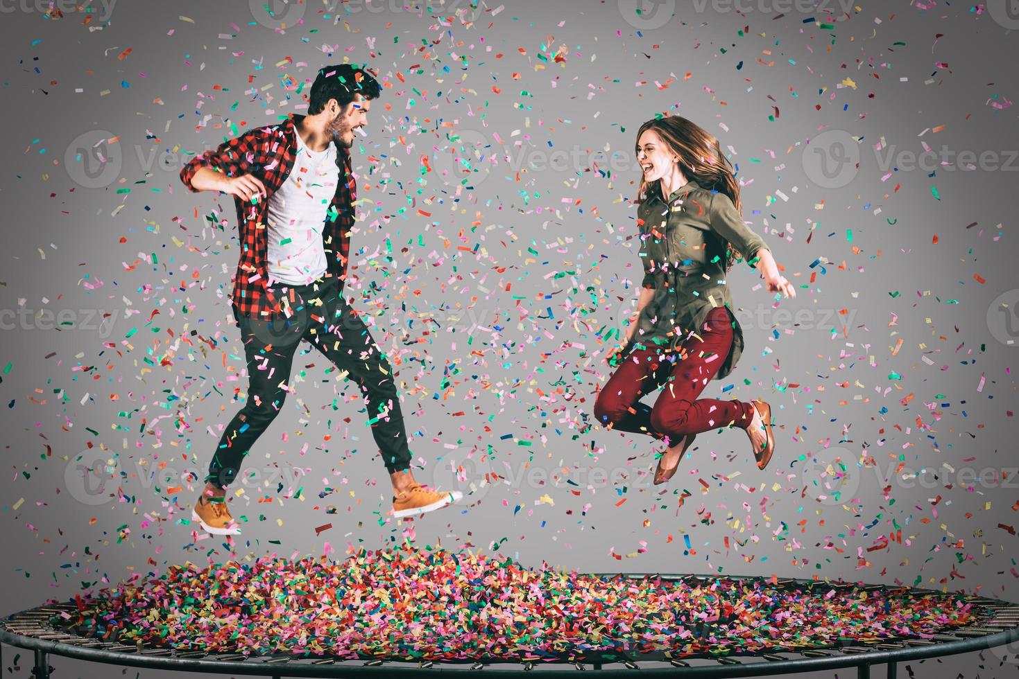 diversión en el aire. toma en el aire de una hermosa pareja joven y alegre saltando en un trampolín junto con confetti a su alrededor foto