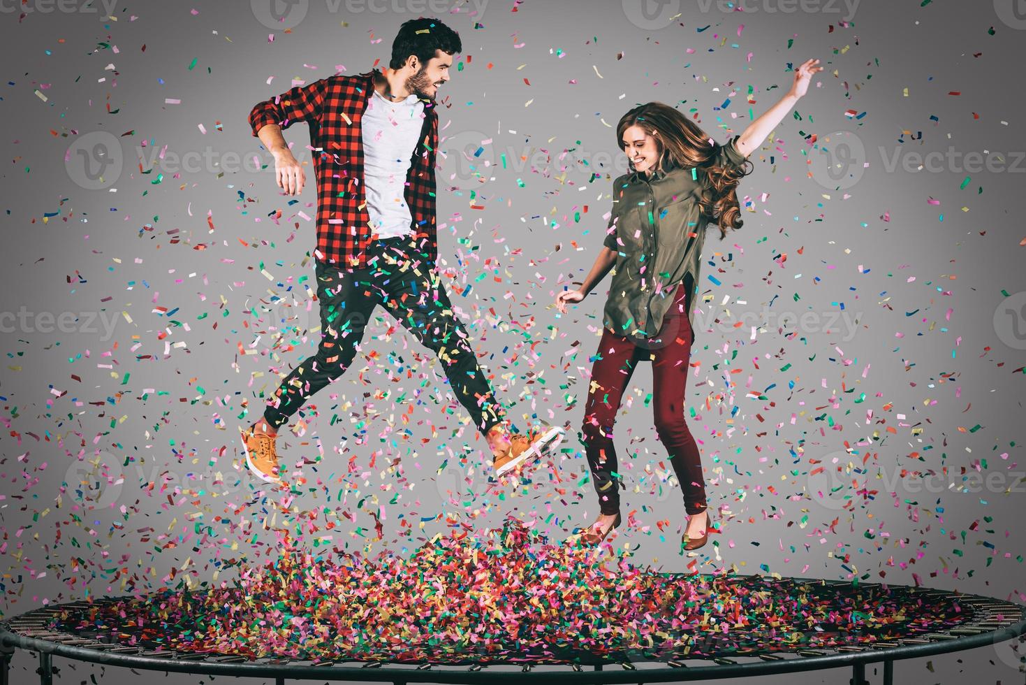 diversión de confeti. toma en el aire de una hermosa pareja joven y alegre saltando en un trampolín junto con confetti a su alrededor foto