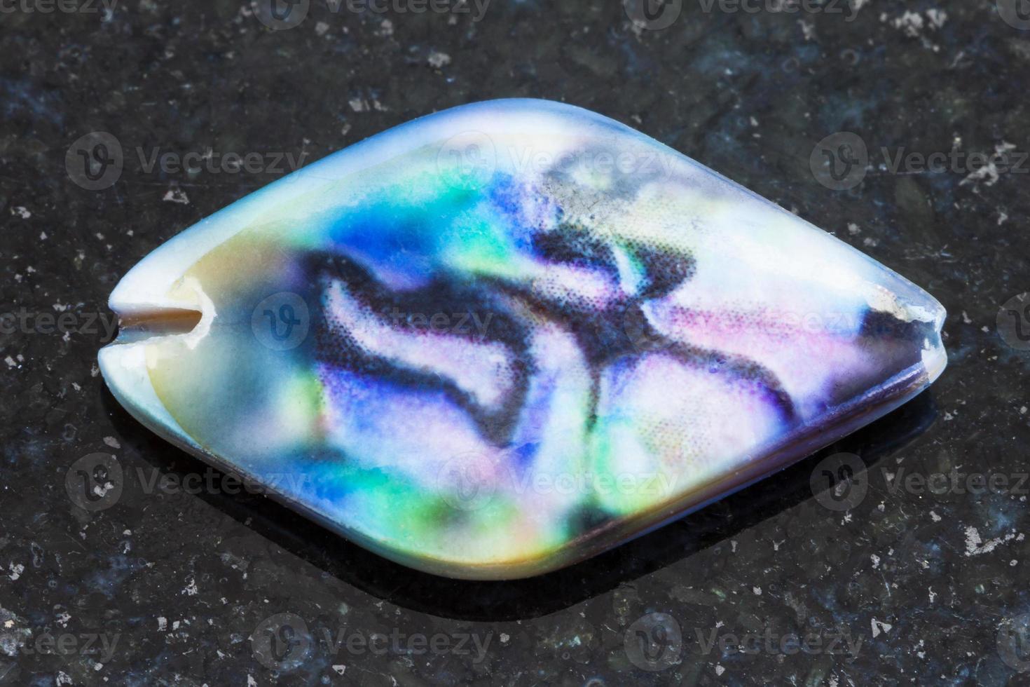 iridescent bead from haliotis shell on dark photo