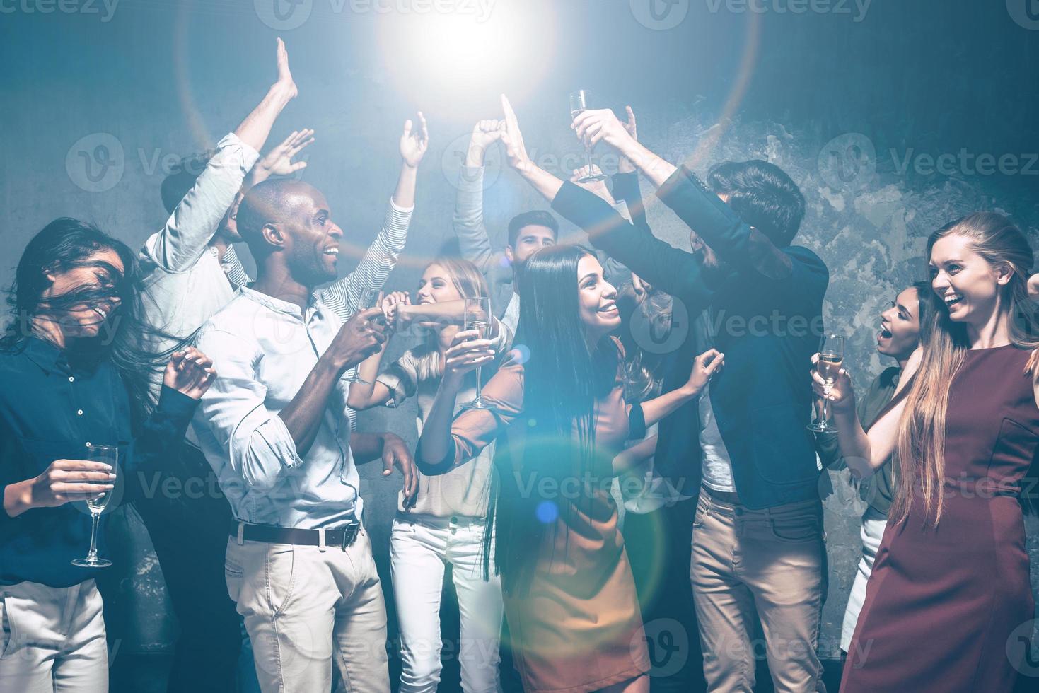 Enjoying cool party together. Group of beautiful young people dancing together and looking happy photo