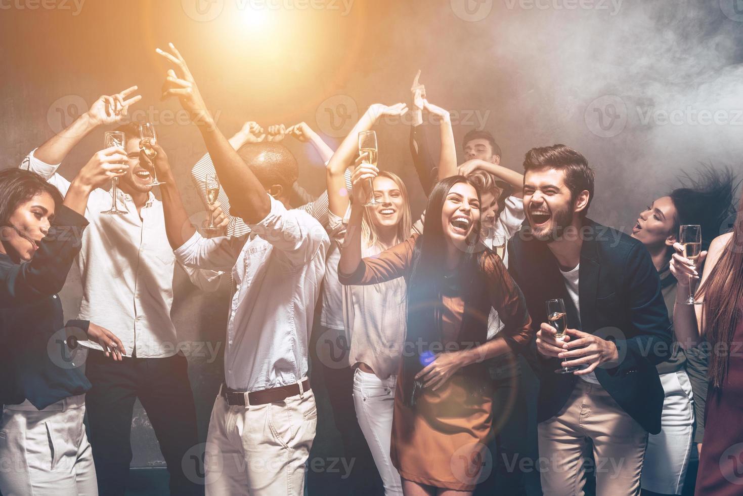 diversión es todo lo que necesitan esta noche. grupo de hermosos jóvenes bailando juntos y luciendo felices foto