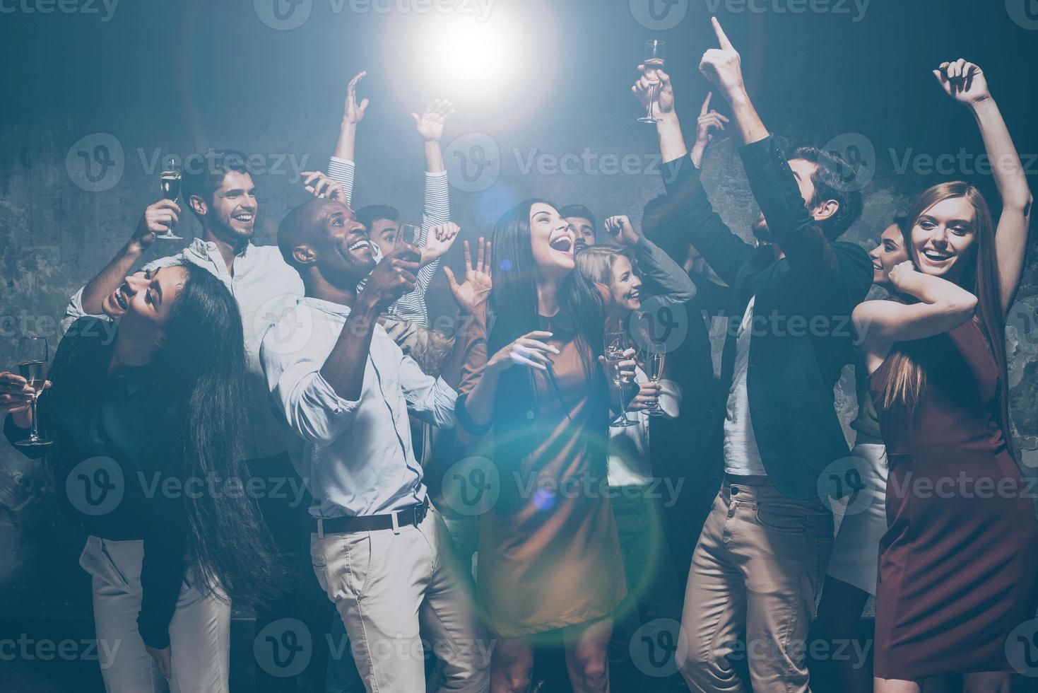 Put your hands up in the air Group of beautiful young people dancing together and looking happy photo