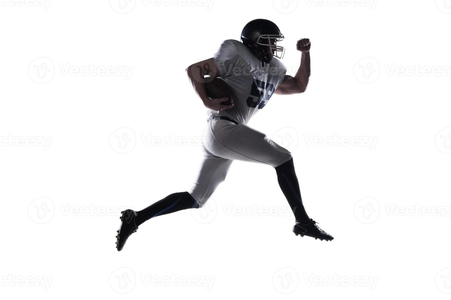 Forward to the victory  Side view of American football player holding ball and jumping against white background photo