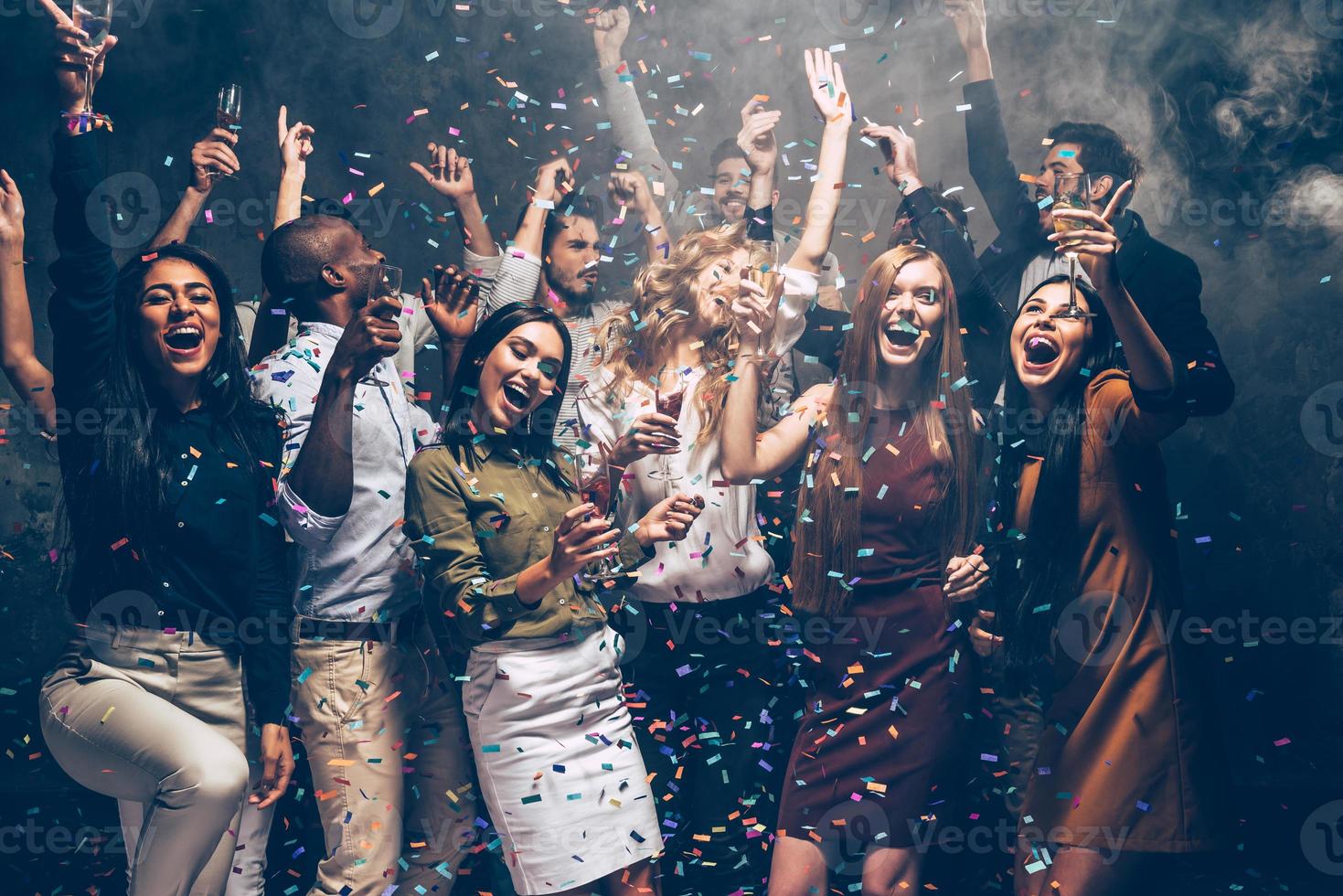 Party fun. Group of beautiful young people throwing colorful confetti and looking happy photo