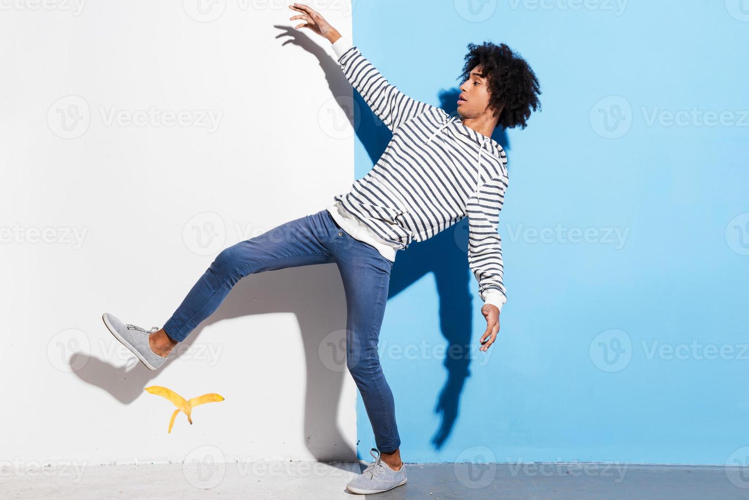 Watch your step Handsome young African man slipping against colorful background photo