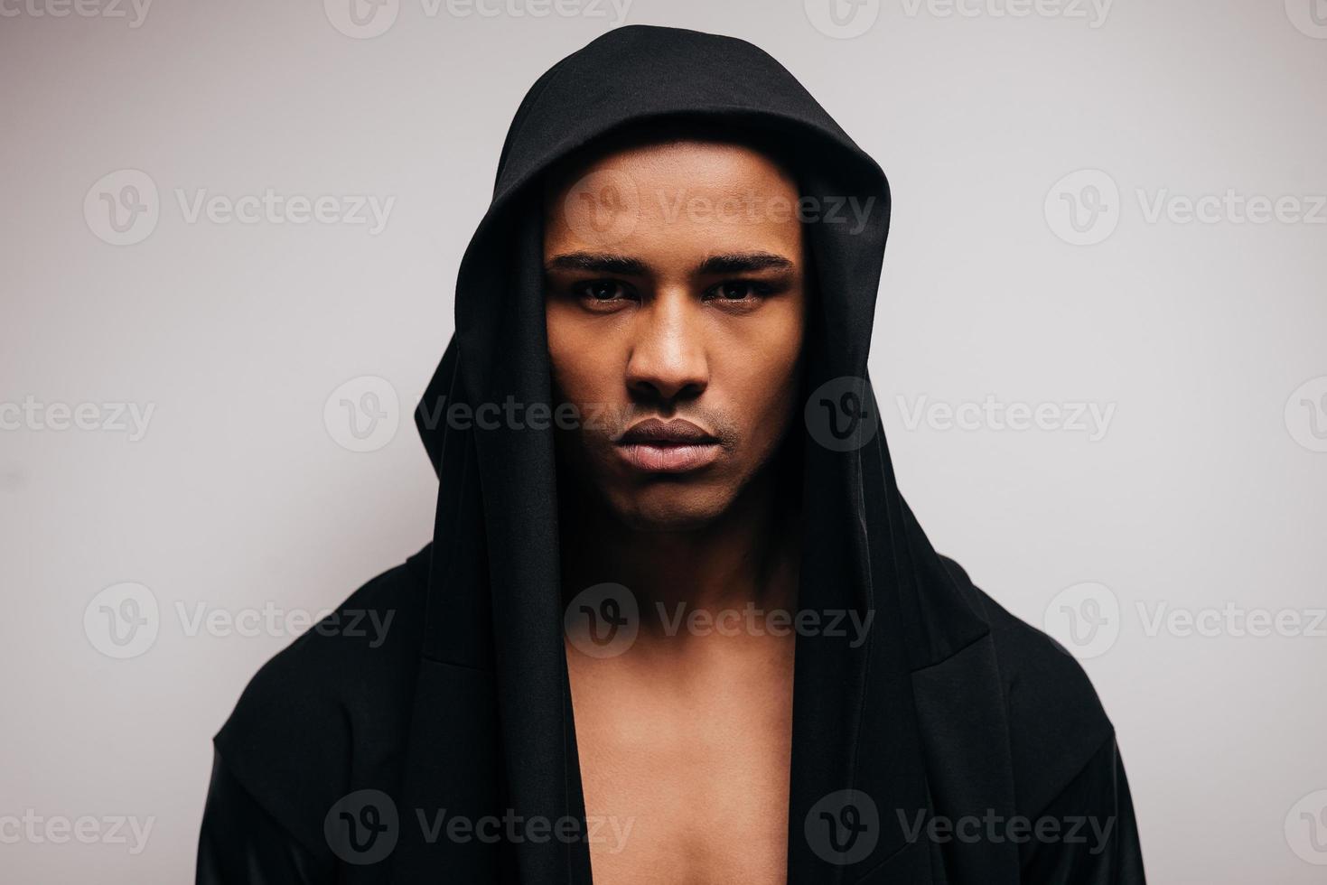 Confident in his style. Confident young African man in hooded shirt looking at camera while standing against grey background photo