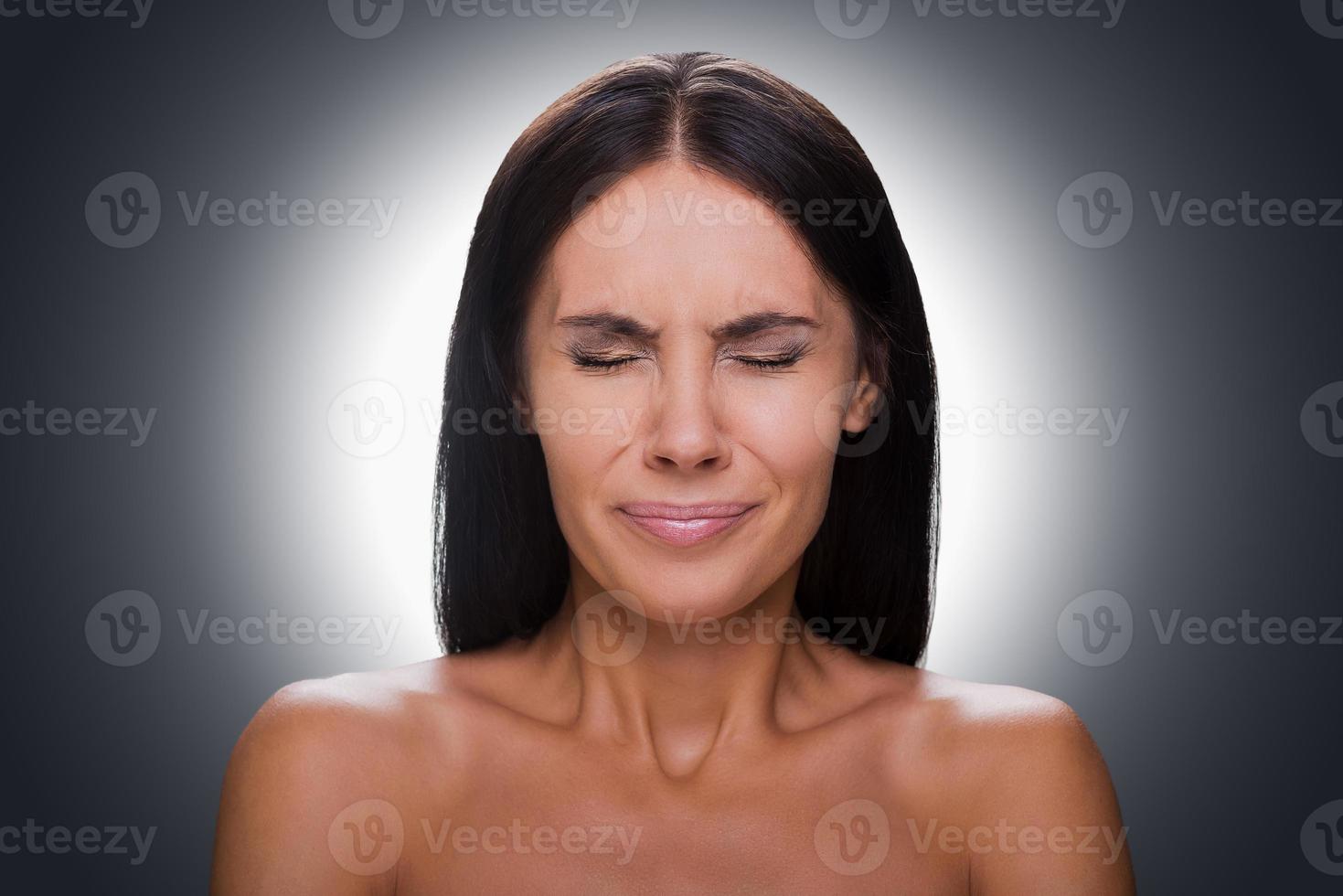 Failed again Portrait of frustrated young shirtless woman keeping eyes closed while standing against grey background photo