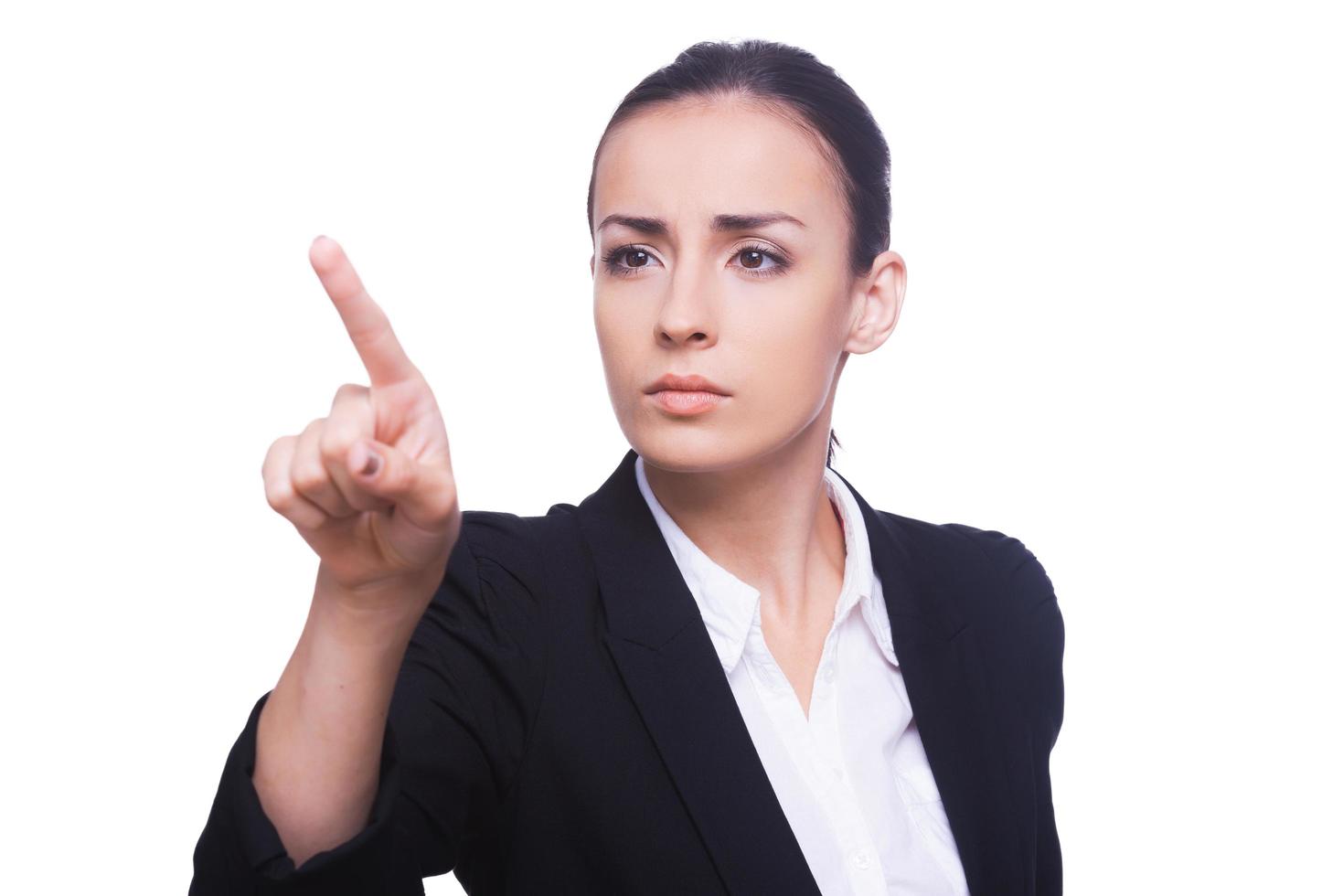 Touching a transparent wipe board. Confident young woman in formalwear touching a transparent wipe board while standing isolated on white photo