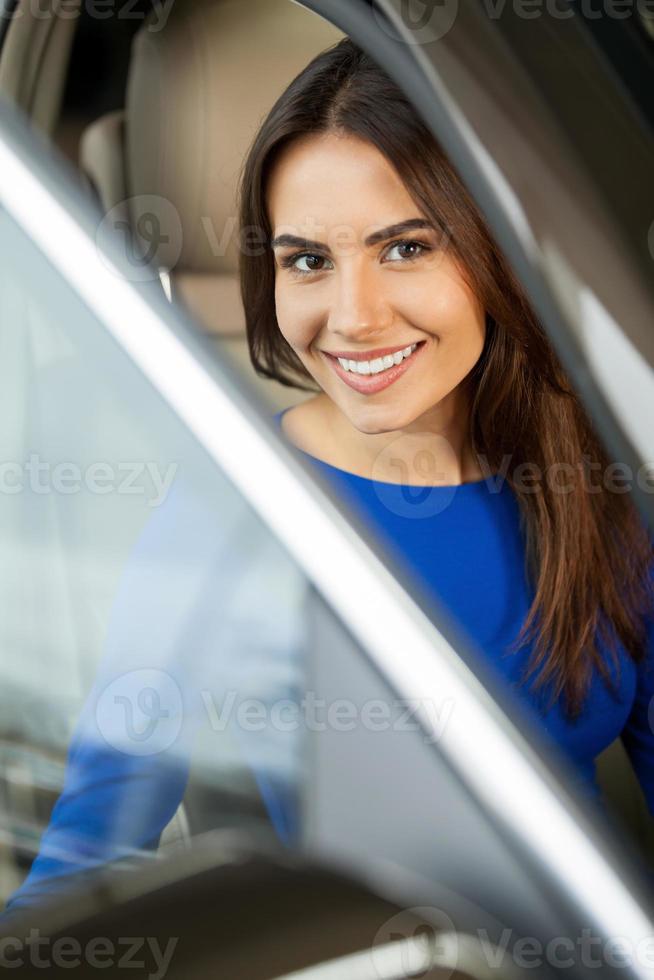 She has bought her dream car Attractive young woman sitting at the front seat of the car looking at camera photo