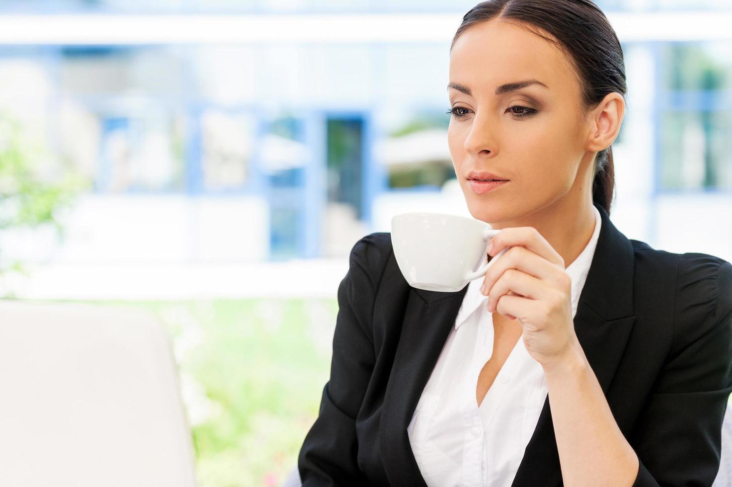 Coffee break. Attractive young businesswoman in formalwear working on laptop and smiling while sitting in sidewalk cafe photo