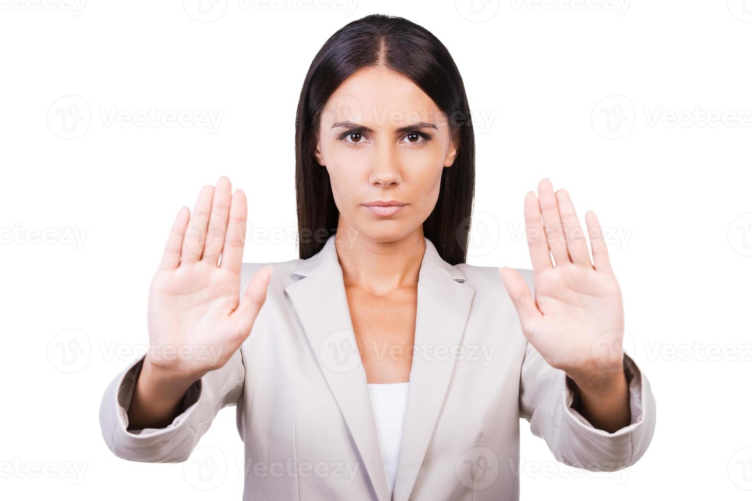 Stop it Confident young businesswoman in suit stretching out hands and showing her palms while standing against white background photo