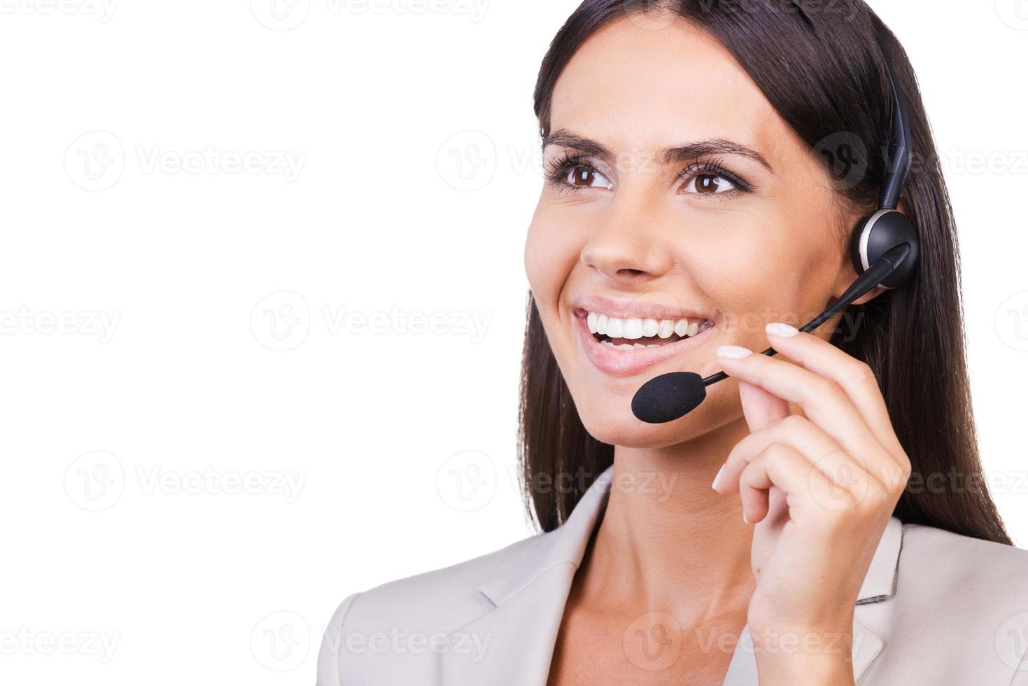 Always ready to help. Beautiful young businesswoman adjusting her headset and smiling while isolated on white background photo