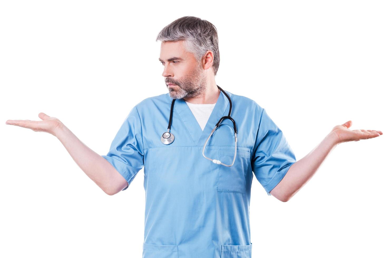 Making a choice. Confident mature surgeon holding copy spaces in both hands while standing isolated on white photo