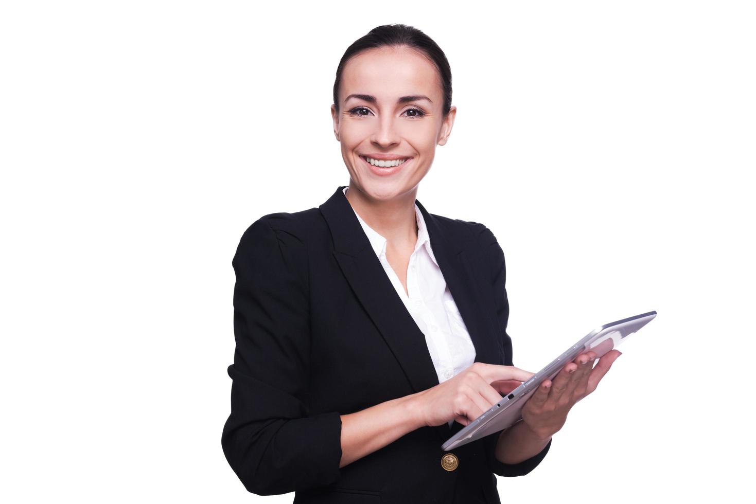 Businesswoman with digital tablet. Confident young woman in formalwear working on digital tablet and smiling while standing isolated on white photo