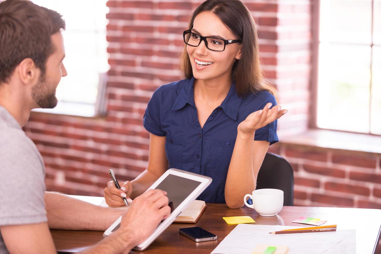 Discussing business. Two cheerful business people in casual wear talking and gesturing while sitting at the table photo