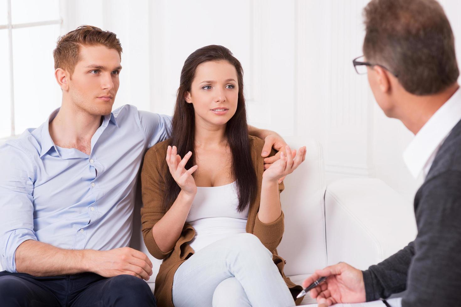 necesitan un consejo experto. Una pareja joven frustrada contándole sus problemas de relación al psiquiatra. foto