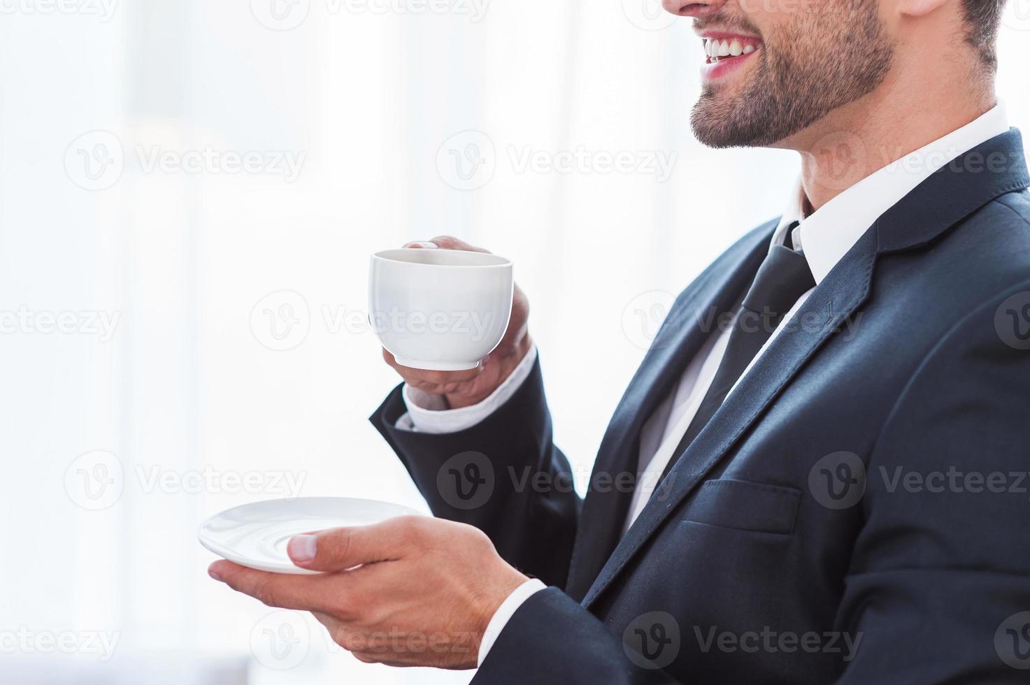 Coffee break. Side view of thoughtful young businesswoman in suit drinking coffee and looking away while sitting at the chair photo