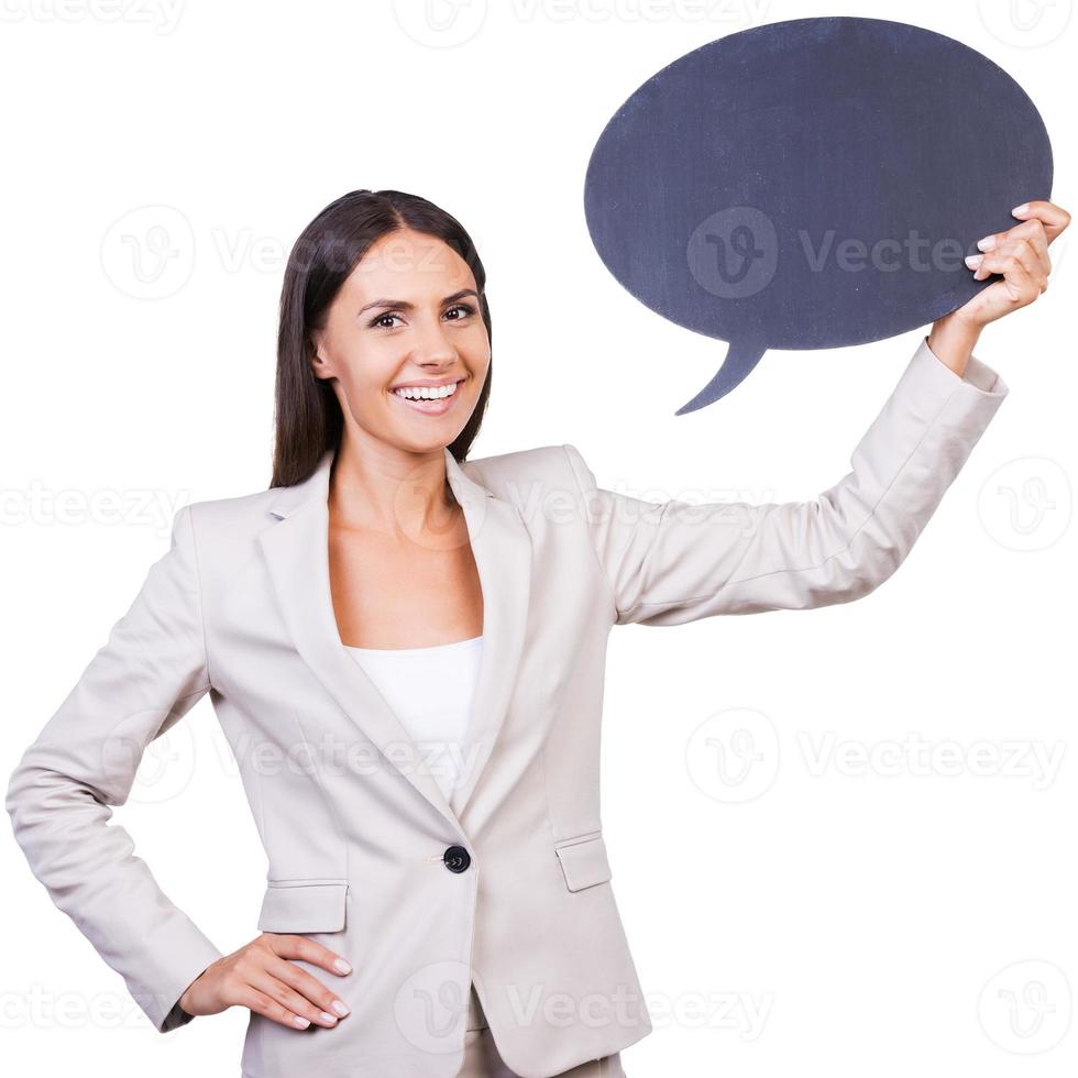 Copy space on her banner. Beautiful young businesswoman in suit holding empty banner and smiling while standing against white background photo