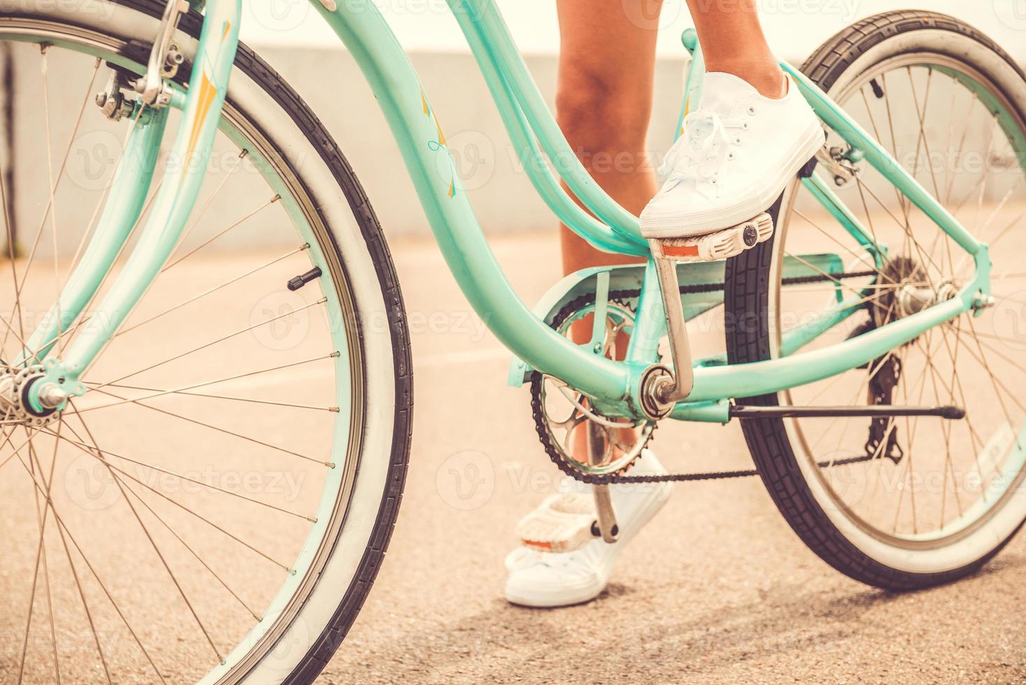 Ready to ride. Close-up of young woman holding her foot on bicycle pedal photo