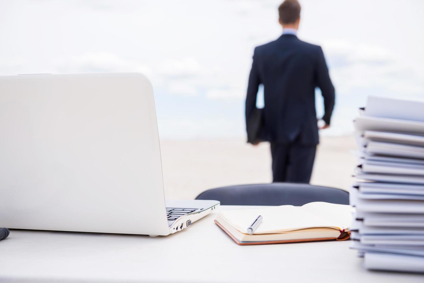 cansado de la vida de oficina. vista trasera del hombre en ropa formal alejándose de su lugar de trabajo foto