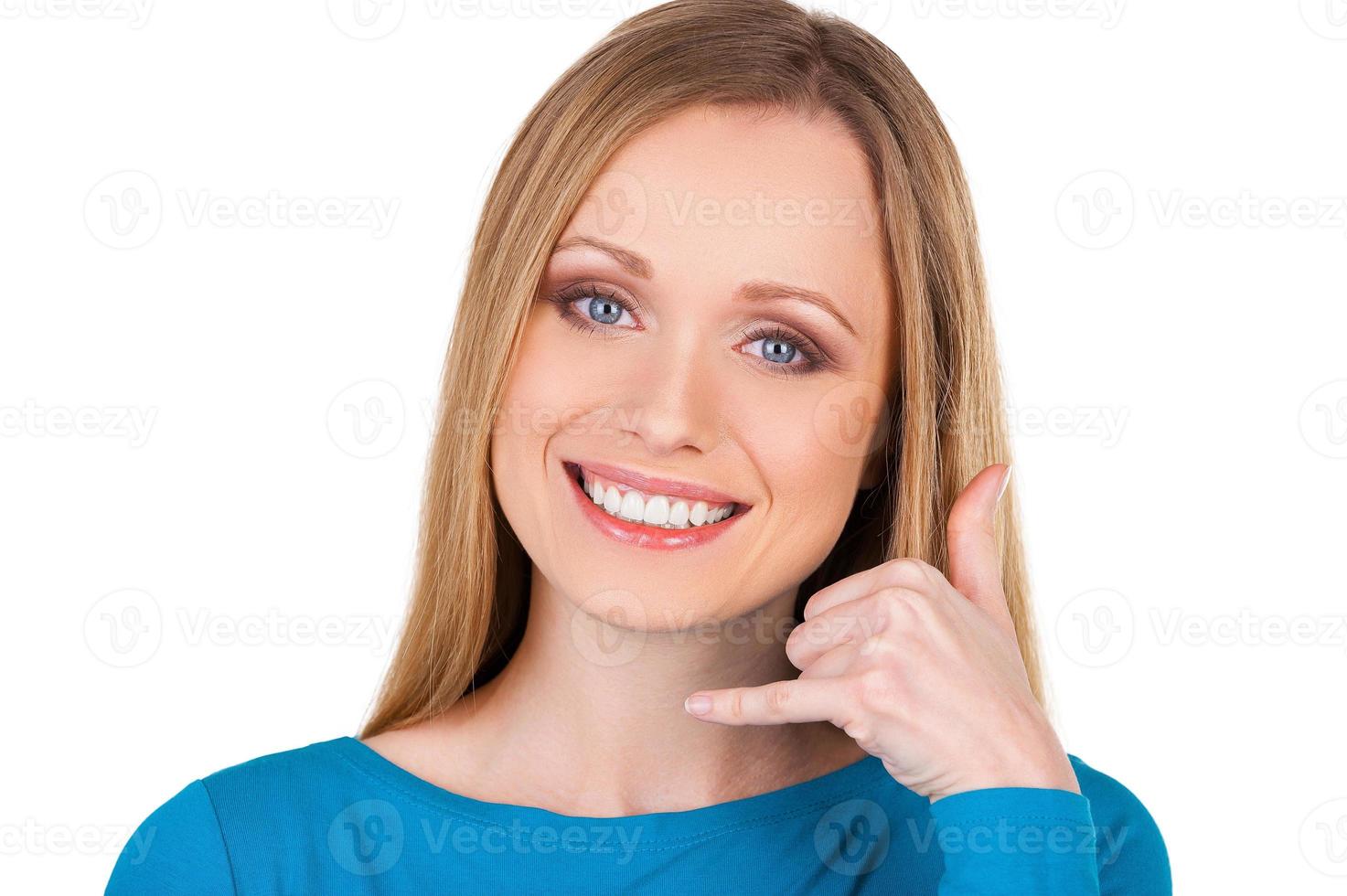 Waiting for your call Beautiful young smiling woman looking at camera and gesturing while standing isolated on white photo