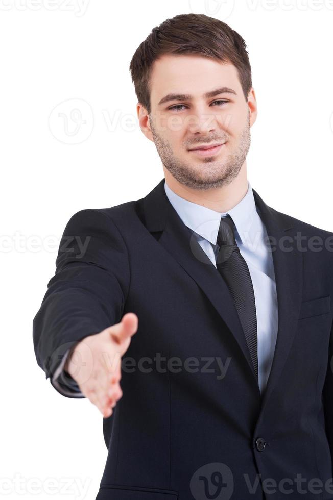 bienvenido a bordo de un joven seguro de sí mismo con ropa formal que estira la mano para temblar mientras está de pie aislado en blanco foto