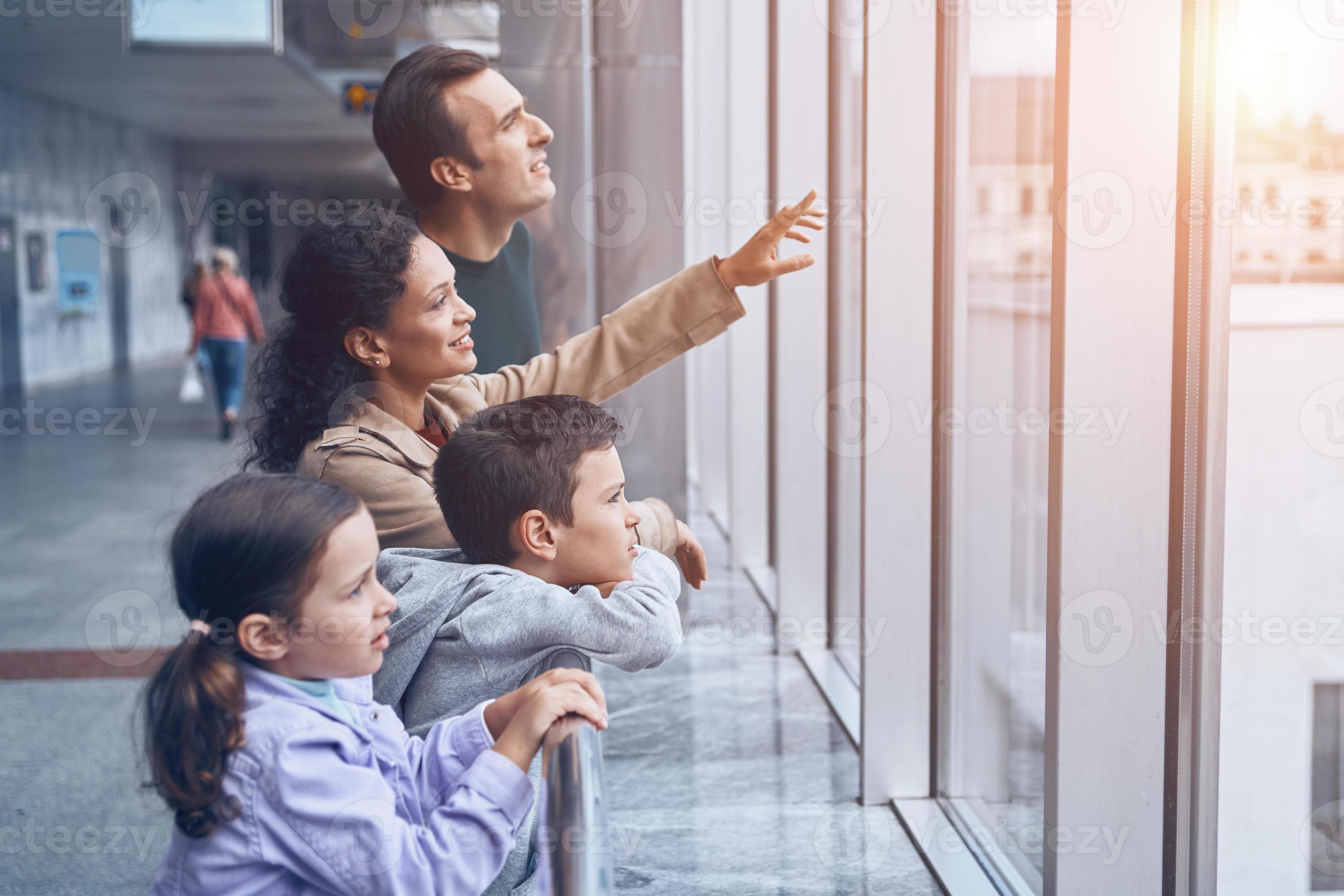 Happy Family With Two Little Kids Looking Through A Window While Happy Family With Two Little Kids Looking Through A Window While