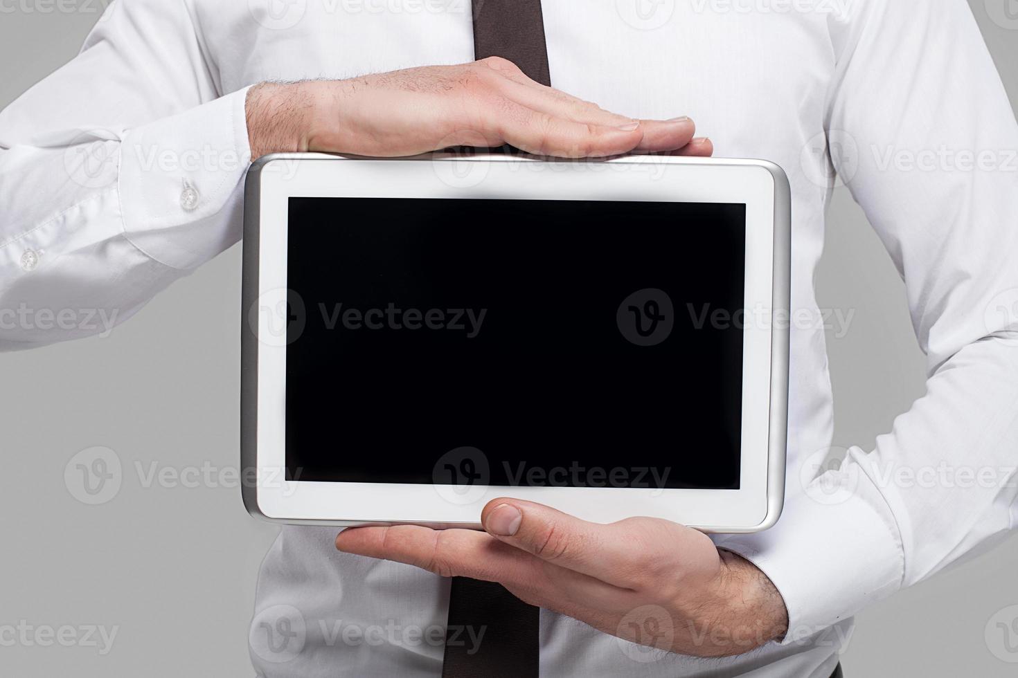 Join a digital age. Cropped image of man in formalwear holding a digital tablet while standing against grey background photo