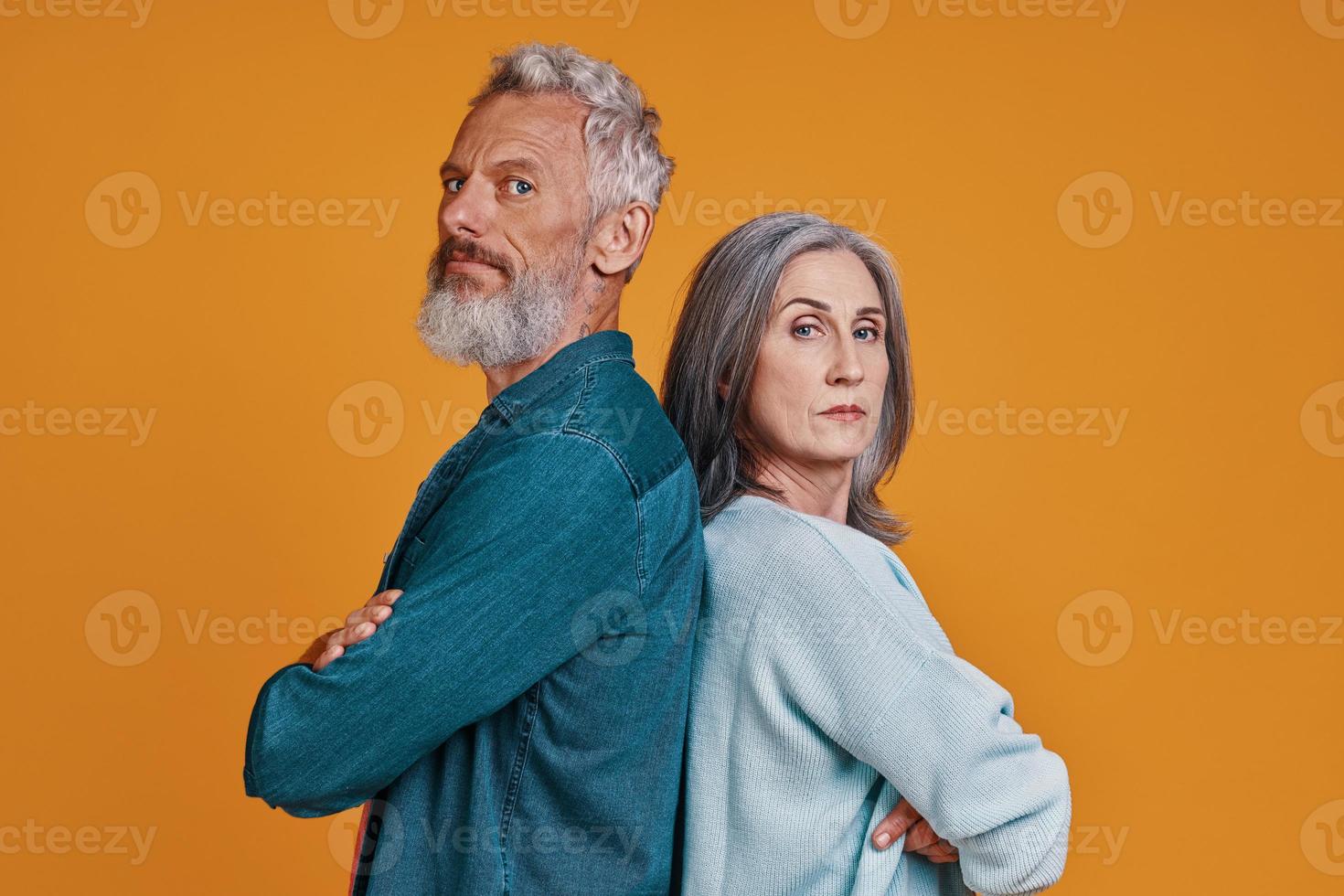 Beautiful senior couple keeping arms crossed and looking at camera photo