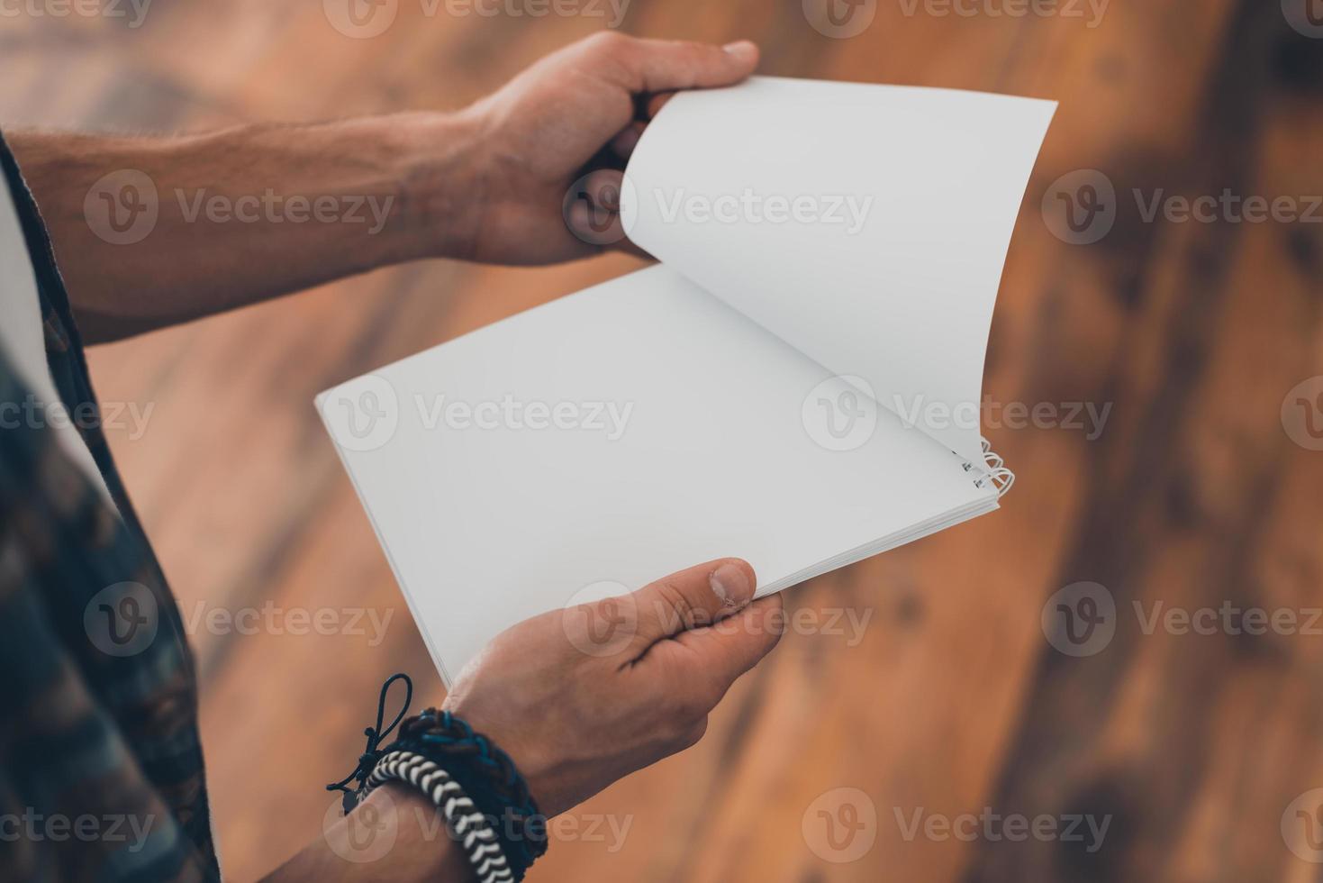 Place for your text. Top view of man turning the page of his note pad while standing on the wooden floor photo