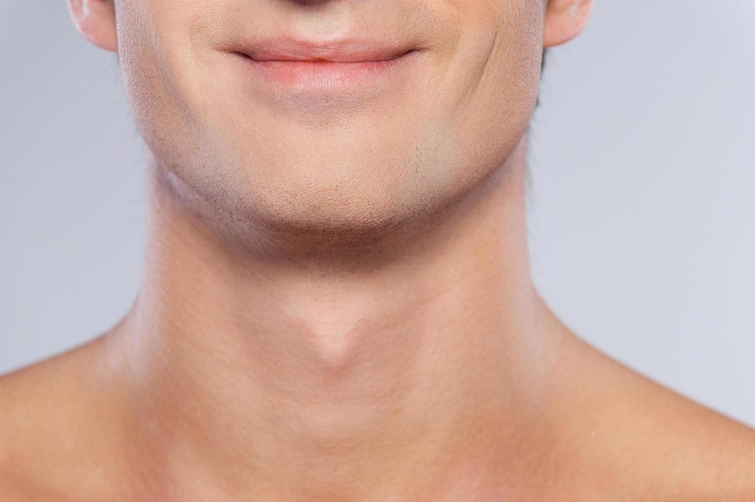 Feeling satisfied. Cropped image of handsome young shirtless man smiling while isolated on grey background photo