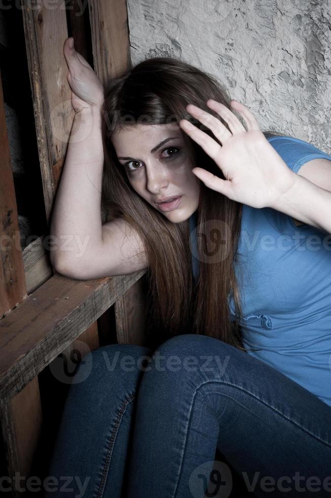 detenerlo vista superior de una joven aterrorizada llorando y estirando la mano mientras se apoya en la pared oscura foto