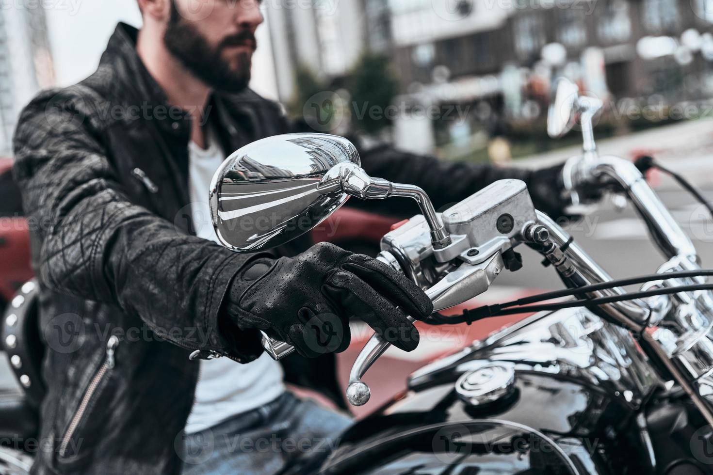 Feeling the freedom. Close up of young man sitting on the motorbike while spending time outdoors photo