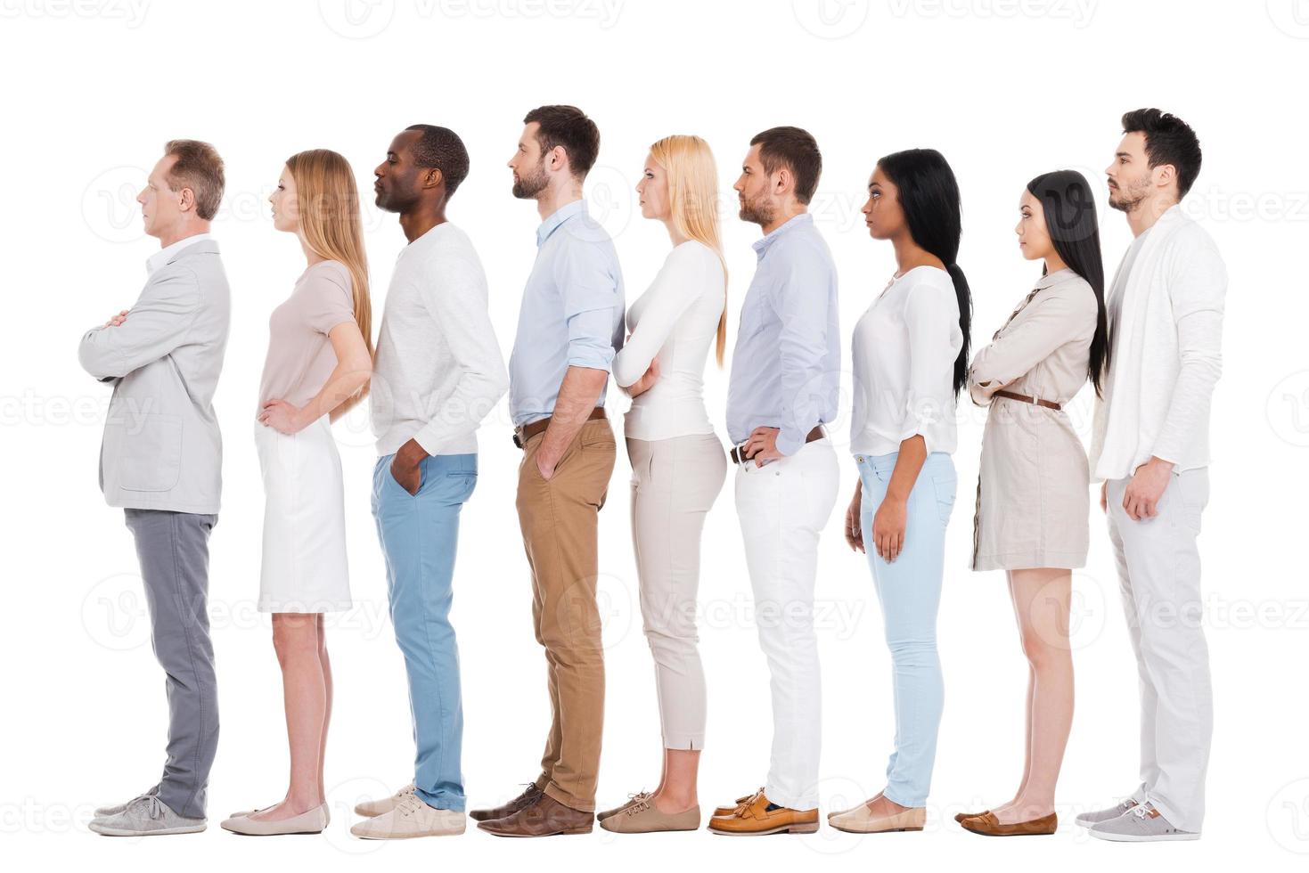 Standing in a row. Full length of confident multi-ethnic group of people in smart casual wear looking away while standing in a row and against white background photo