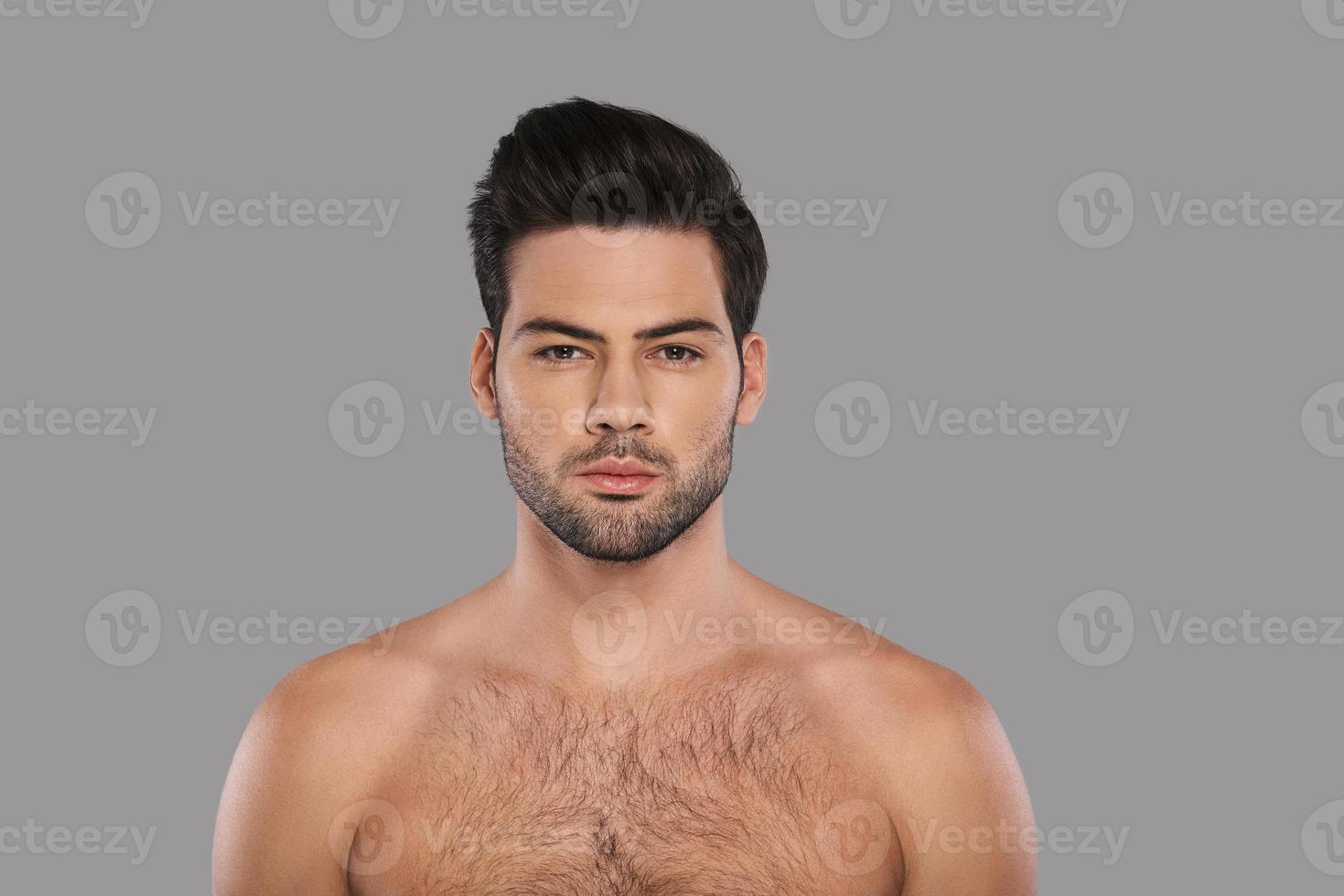 Real man. Handsome young man looking at camera while standing against grey background photo