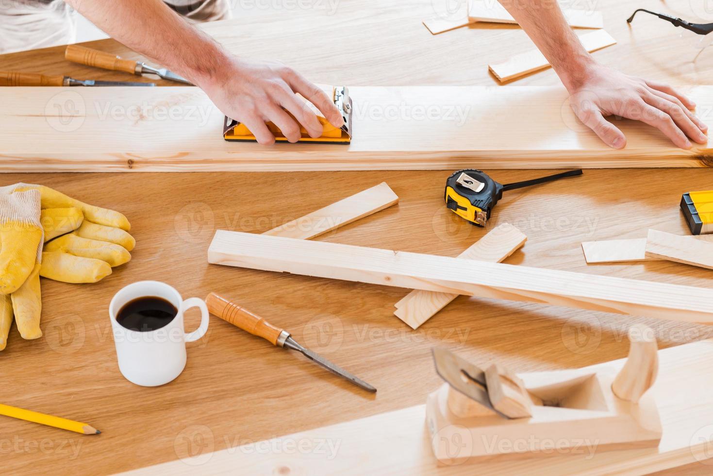 Working tools for carpenter. Close-up of male carpenter working at the wooden table with diverse working tools laying on it photo