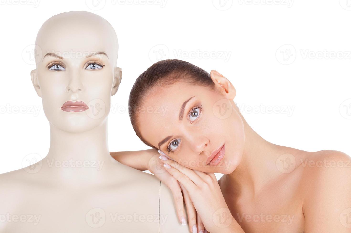 Beautiful and individual. Beautiful young shirtless woman leaning at the mannequin and looking at camera while standing isolated on white background photo