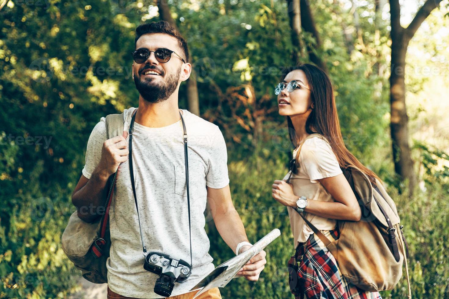 feliz pareja joven explorando nuevos lugares y sonriendo mientras camina al aire libre foto