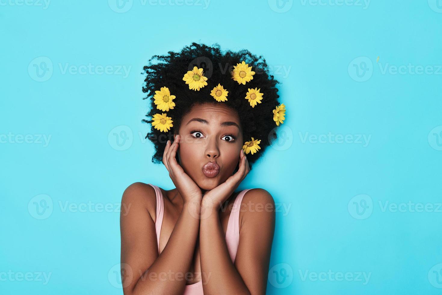 sentirse libre de volverse loco. vista superior de una atractiva joven africana mirando la cámara y frunciendo el ceño mientras está acostada sobre fondo azul foto