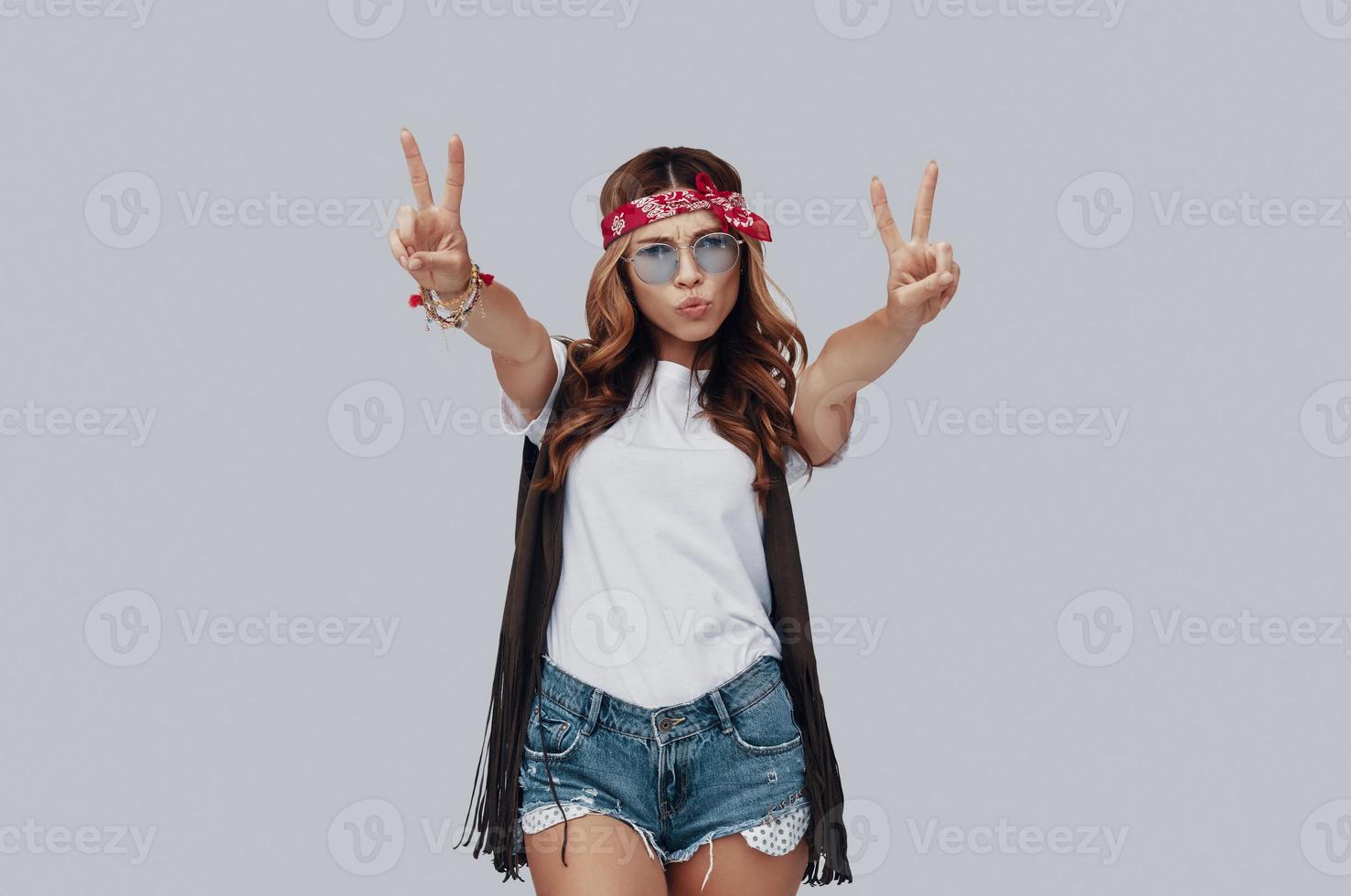 Attractive stylish young woman looking at camera and puckering while standing against grey background photo