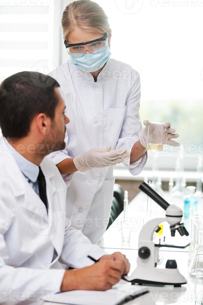 This is what we are testing today. Side view of two scientists making experiments while sitting in the laboratory photo
