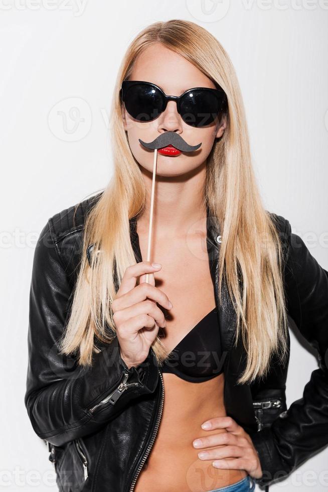 Just for fun. Confident young woman in black bra and leather jacket making a face while standing against white background photo