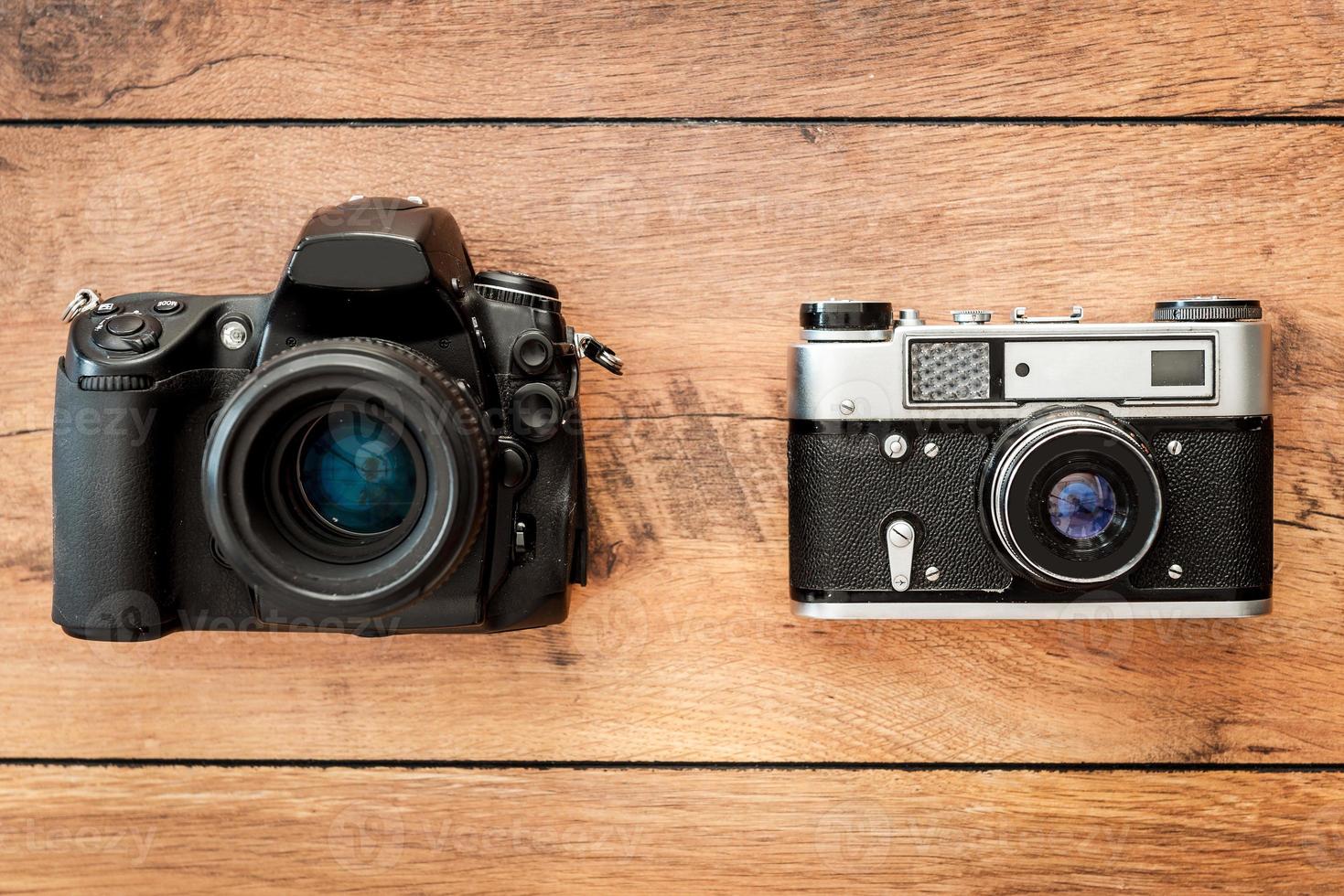 Modern or retro Top view of two cameras laying on the wooden grain photo