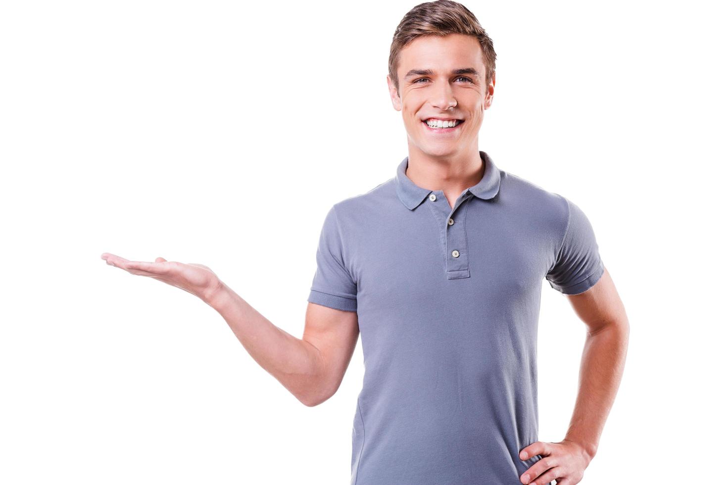 copie el espacio en su mano. un joven apuesto que sostiene un espacio para copiar en la mano y sonríe mientras está aislado de fondo blanco foto