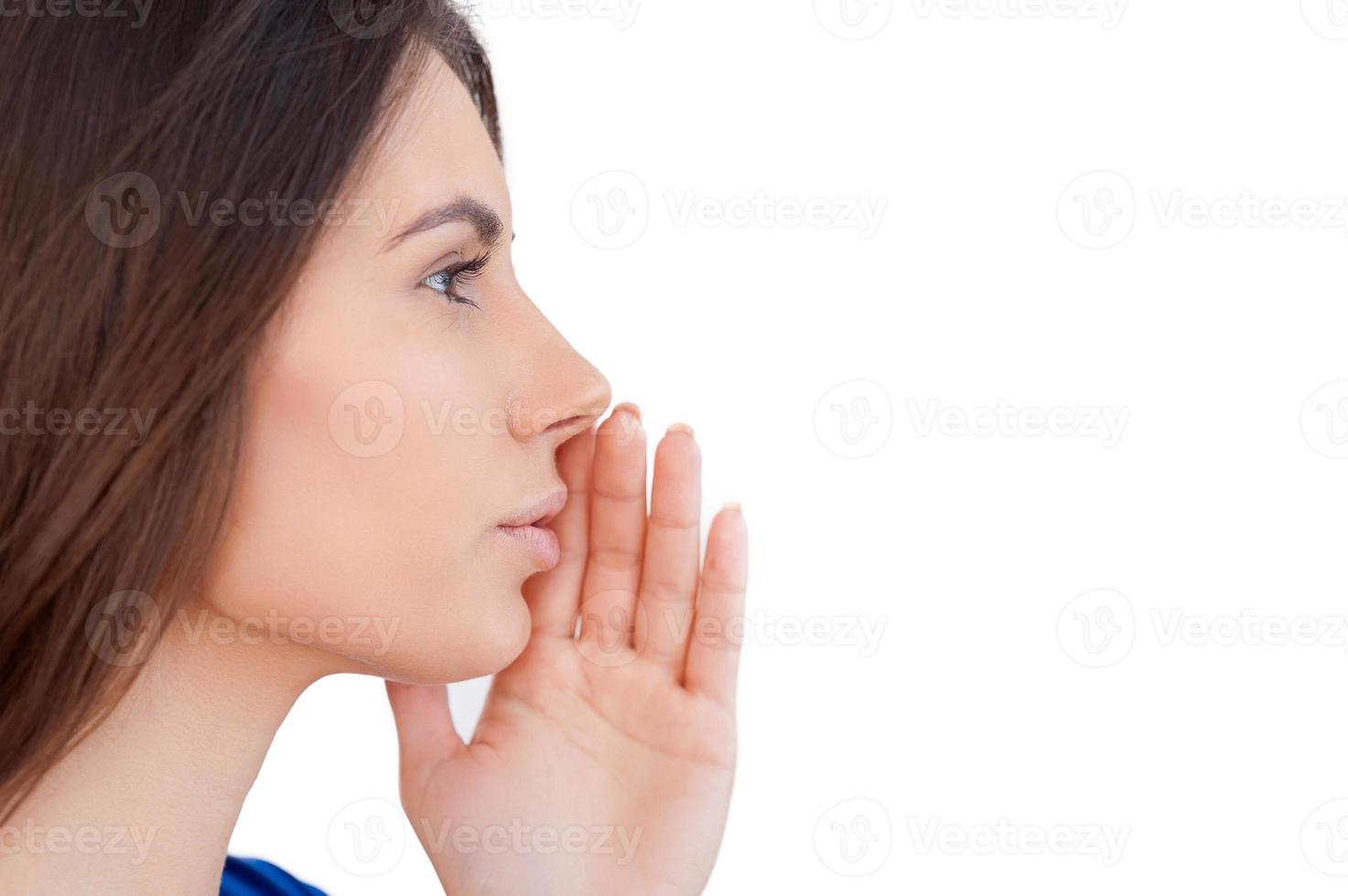 Telling gossips. Side view of young woman telling gossips while isolated on white photo