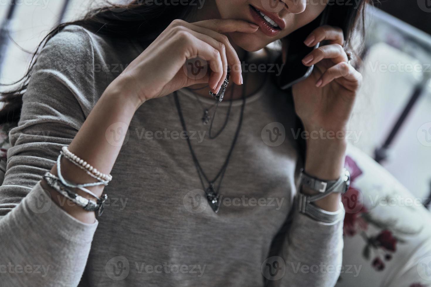 escuchando a su amiga. primer plano de una mujer joven con la mano en la barbilla mientras habla por teléfono inteligente foto